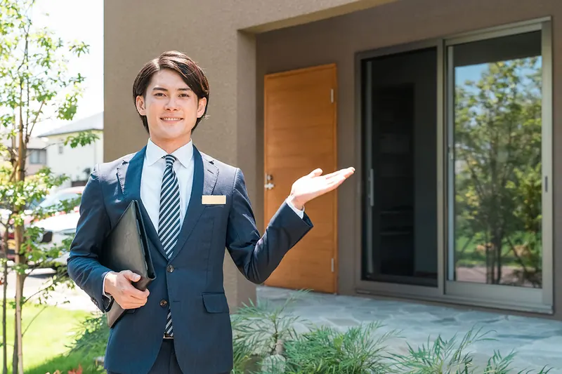戸建て住宅の前で購入相談に応じるレントレードの営業担当者
